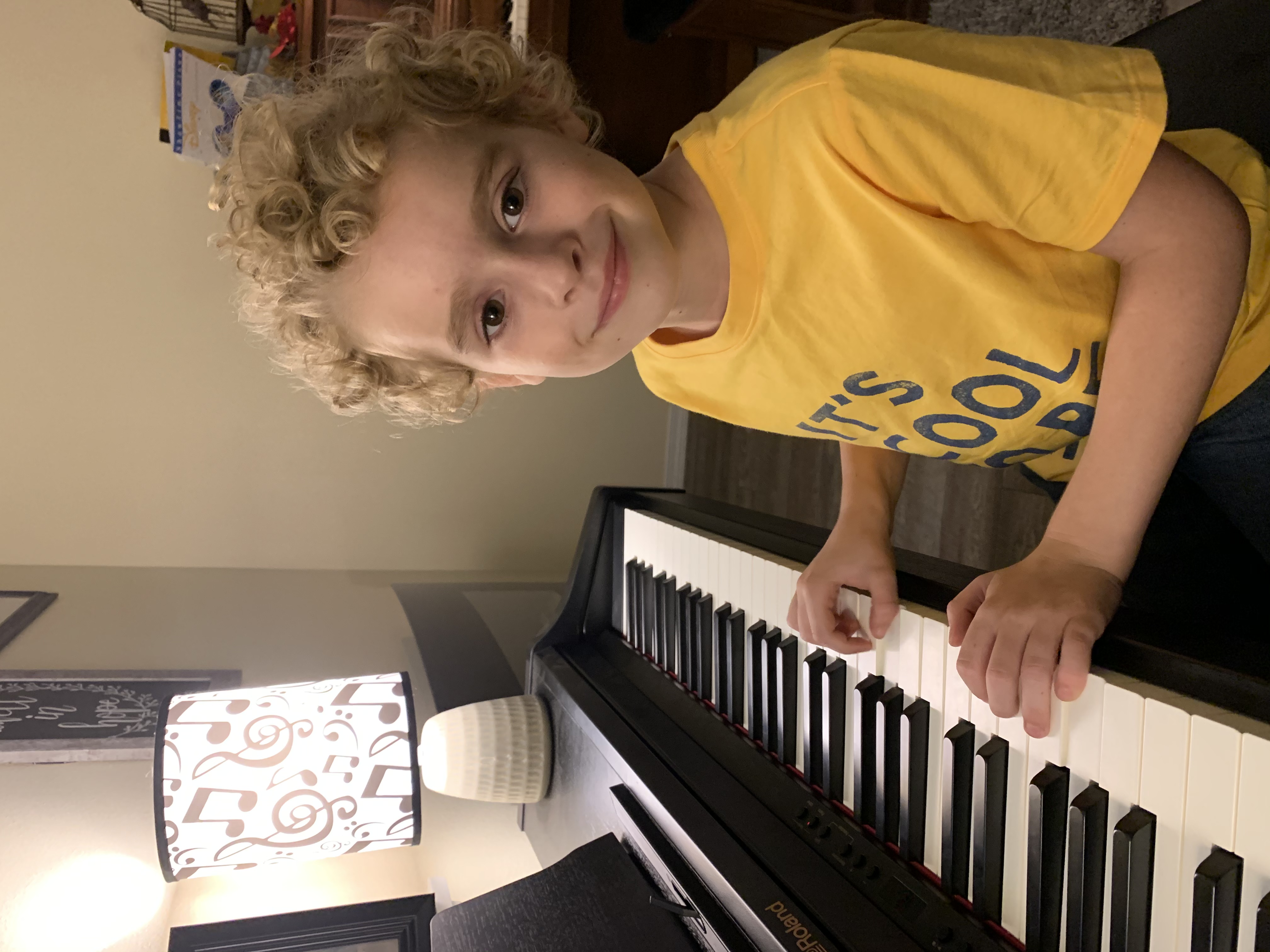 Young Leland at the piano at home, smiling at the camera